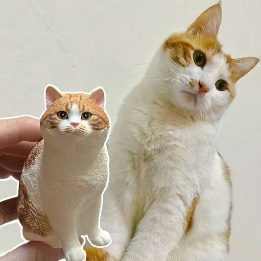 A realistic custom cat figurine placed beside the real orange and white cat, showing the lifelike details.